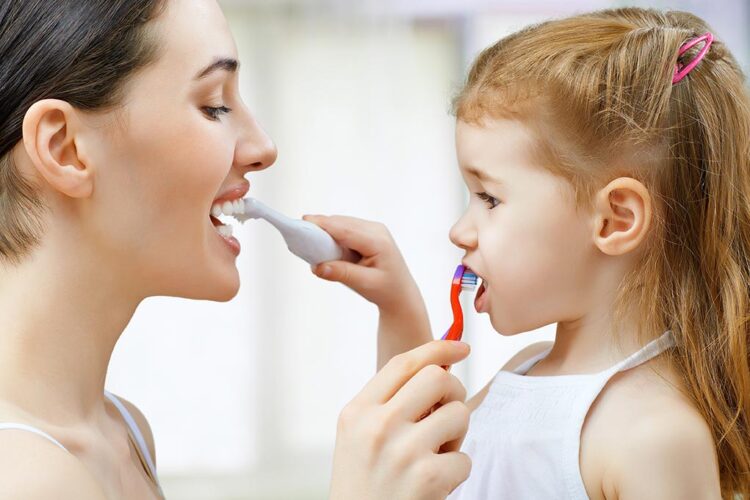 madre con su hija cepillando dientes
